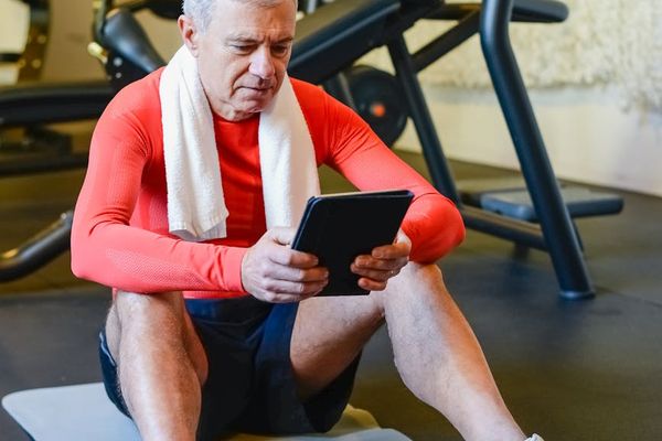 A focused man planning his workout routine on a tablet.