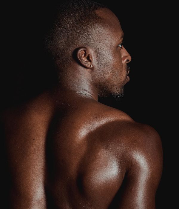 Man performing a powerful strength exercise in a dark room with mint light.
